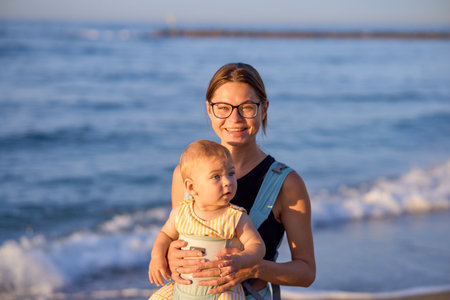 Young mother with her baby boy on the beach in the evening.の写真素材