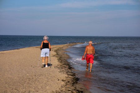 Elderly couple walking on the beach in the summertime.の写真素材