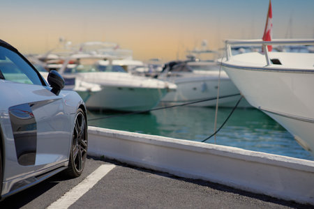 White sport car parked on a pier with boats in the background.の写真素材