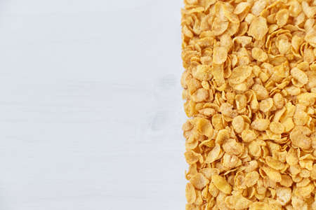 A frame lined with corn flakes. Cornflakes scattered on a wooden table.
