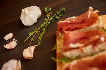 Sandwiches made from hand-made rye bread and thin chopped fresh bacon. Succulend bacon on a wooden board. Fresh green thyme.の写真素材