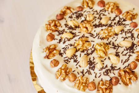 Homemade pie with white topping and chocolate chips on a white wooden table. A large delicious pie with walnuts.の写真素材
