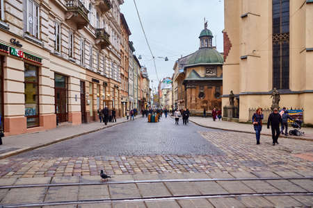 Lviv, Ukraine - November, 2017. Central pedestrian street of Lviv. Many tourists walk around the old city. An ancient church in the center of a European city.のeditorial素材