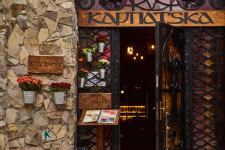 Lviv, Ukraine - November, 2017. Entrance to the restaurant of Karpatska with lights in the background. A metal wrought-iron door with a wooden sign.のeditorial素材