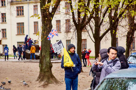 Lviv, Ukraine - November, 2017. Guide to Lviv calls tourists for an excursion. A man with a British flag offers a free tour.のeditorial素材