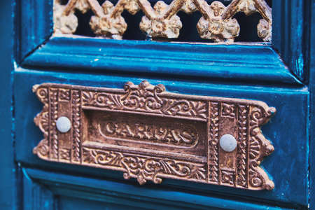 A hole for mail in a blue wooden door, handmade by metal. Slot for correspondence is decorated with ornament. Close-up, macroの写真素材