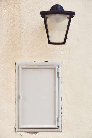 Gray empty metal banner on a light wall. Composition with a lamp and a vintage wall for the inscription on the gray door. Free space for advertising and inscriptions. Soft vintage photo processingの写真素材