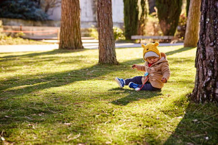 Lisbon, Portugal - January, 2018. Gulbenkian park and garden. Mom and son are playing in the park. A little boy is sitting on the grass, and a woman is taking pictures of him on a mobile phoneのeditorial素材