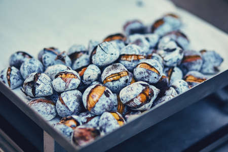 Fried half-opened chestnuts on a metal tray are sold in the city center. Shells with a touch of soot. Portugal's national food is very popular with touristsの写真素材