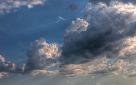 Cumulus clouds with rays of sun shining throughの写真素材