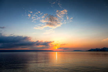 Sun going down on a horizon over a lakeの写真素材