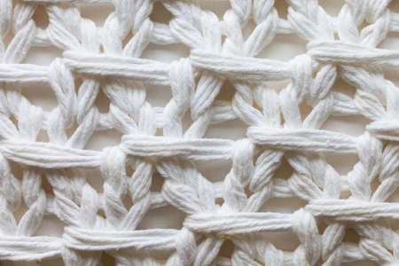Knotted white strings on a white fabric background
