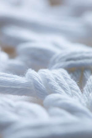 Closeup of knotted white strings on a white fabric backgroundの写真素材