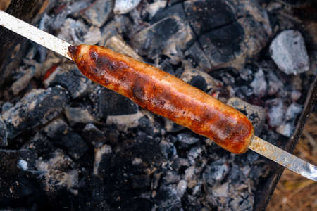 Preparation of sausages on outdoor charcoal grill.の写真素材