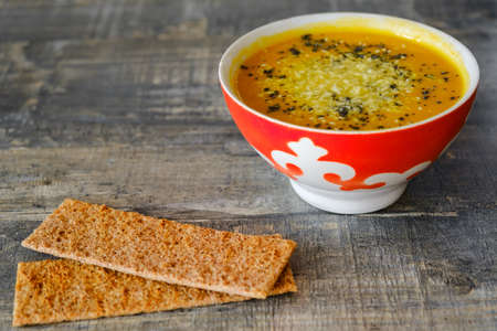 Pumpkin soup with bread on a wooden tabletop, side viewの写真素材