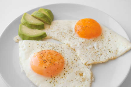 Scrambled eggs with avocado and specialy on a white plate on a white background. Close-up, top viewの写真素材