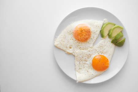 Scrambled eggs with avocado and specialy on a white plate on a white background with blank copy space, top viewの写真素材