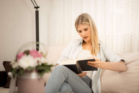 A beautiful girl sitting in a pleasant atmosphere and reading a book.