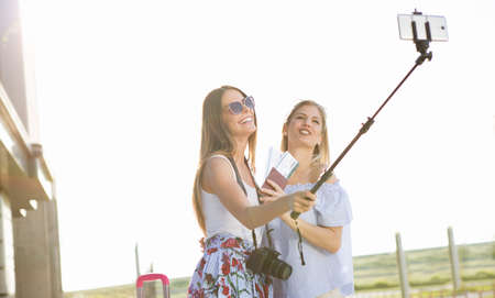 The two sisters are waiting for their flight, but before we took off, they must set up a picture on social networks.の写真素材