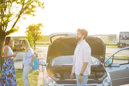 A group of people stayed on the road because their car broke down.の写真素材
