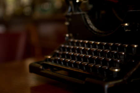 Selective focus on the keyboard key on an old black rustic typewriter on a desk in the office. The typewriter is a lot old so the letters on the keys are almost worn out. Copy space.の写真素材