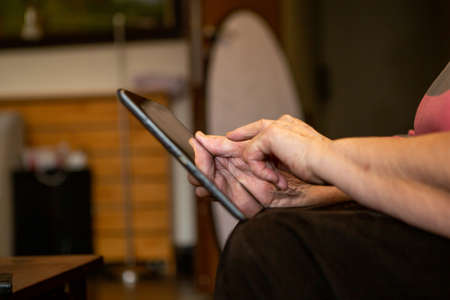 Senior woman's hand touching a touch screen on her laptop tablet. She searches the internet for some...