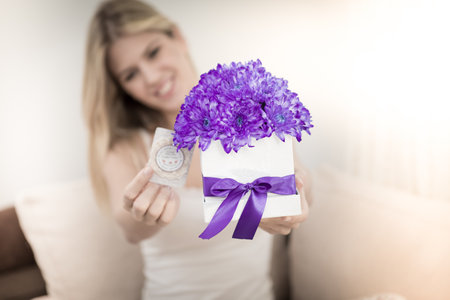 The young blonde holds a bouquet of flowers in her hands in a decorative box she received from a man she loves. She laughs and is very happy.の写真素材