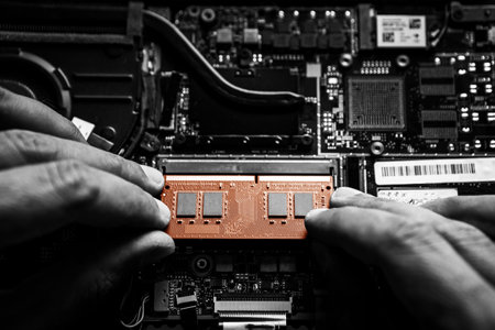 Close-up on the orange RAM memory that the hands of the service technician insert into the slot on the laptop computer.の写真素材