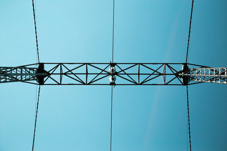 Bottom view of a large metal structure of a high voltage power line. The construction is made of...