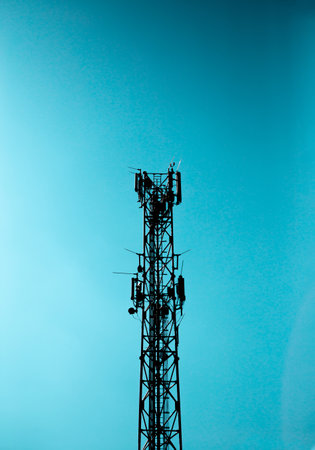 Radio signal tower for mobile telephony and internet. The tower is made of metal construction and behind it is a blue sky.の写真素材