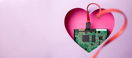The green printed circuit board with microprocessors is located in a pink heart-shaped cavity. All around is purple. Copy Space. Love. Technology. Artificial intelligence. Robotics.の写真素材