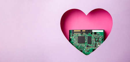 The green printed circuit board with microprocessors is located in a pink heart-shaped cavity. All around is purple. Copy Space. Love. Technology. Artificial intelligence. Robotics.の写真素材