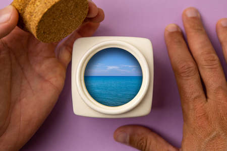Top view of a bowl opened by a man's hand. The blue sea and clouds can be seen through the bowl. The concept of inspiration.の写真素材