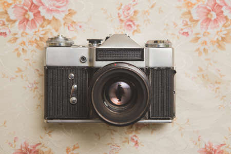 He looked down at an old analog metal camera. The camera is very old and ruined. Below it is an old tablecloth.の写真素材