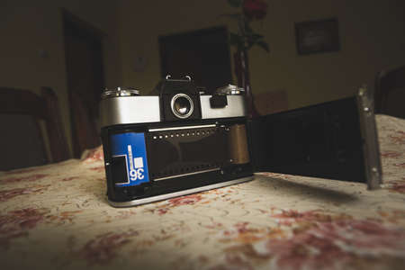 An old analog camera is on the table in the house. The camera is open to the back so you can see the photographic film.の写真素材