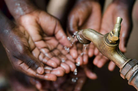 Many African children's hands under a tap with clean, healthy water supply from a tap. Stop Hunger and maladies around the world!の写真素材