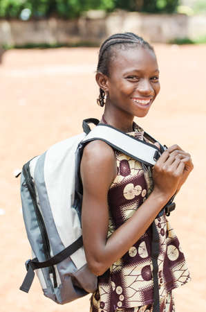 Young girl with backpack looking at camera on blurred backgroundの写真素材