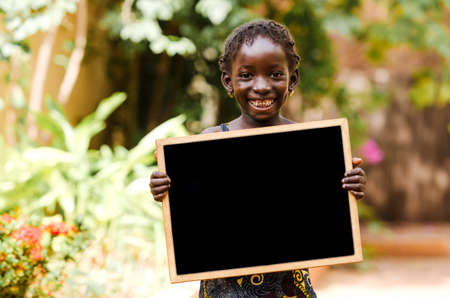 Girl holding signboard and looking at camera with blurred backgroundの写真素材