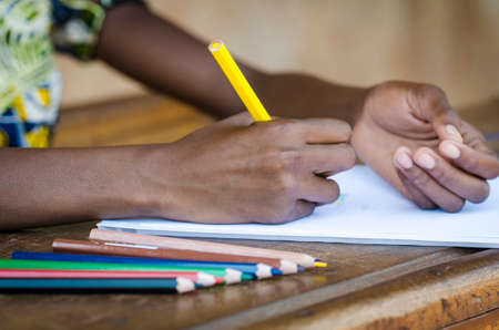 Close up view on female african hands writing on paper with blurred foregroundの写真素材