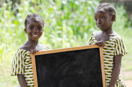 Girls standing and holding signboard and looking at camera in front of buildingの写真素材