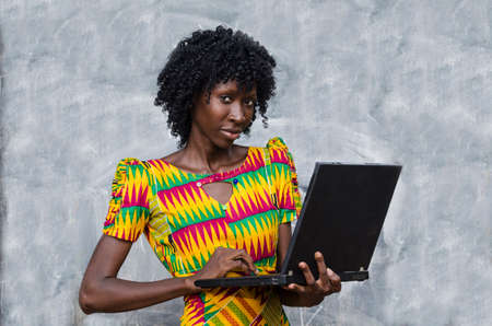 Woman using laptop computer and looking at camera in front of chalkboardの写真素材