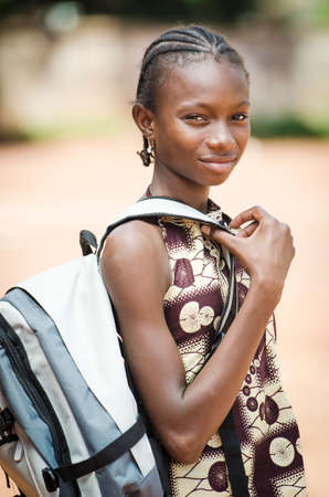 Young girl with backpack looking at camera on blurred backgroundの写真素材