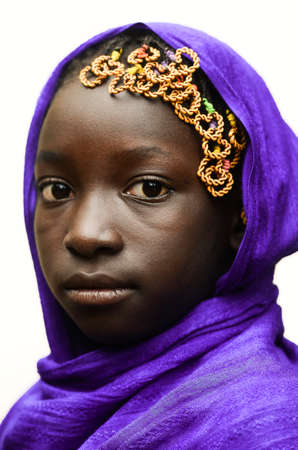 African child with violet African scarf on head, smiling lightlyの写真素材