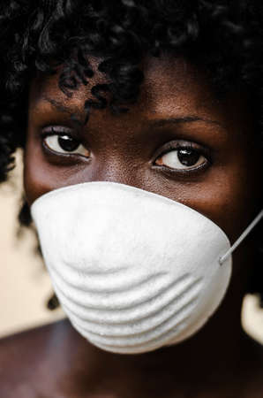 Young woman in filtering half mask and looking at cameraの写真素材