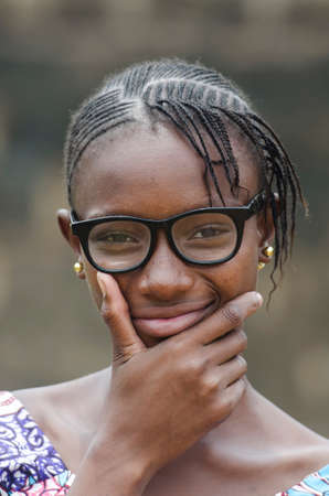 Young african girl in eyeglasses thinking outdoors with blurred backgroundの写真素材