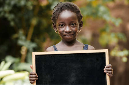 African school girl holding blackboard with copy spaceの写真素材