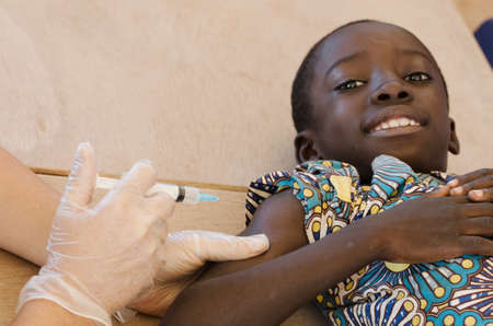 Black boy smiles ready to get his first needle injection from a European volunteerの写真素材