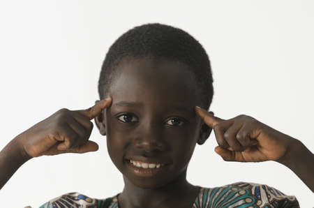African ethnicity boy thinking with his fingers pointing to his head, isolated on whiteの写真素材