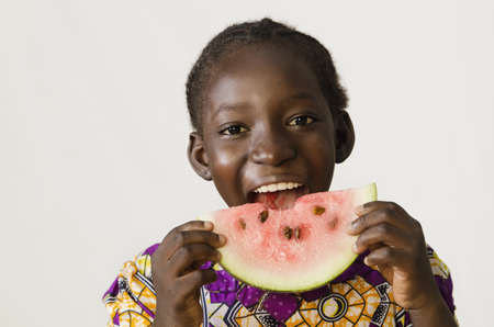 Young African girl eating some watermelon, isolated on whiteの写真素材
