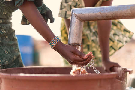 Working West African Young Girl getting Fresh Water for a lack of water symbol